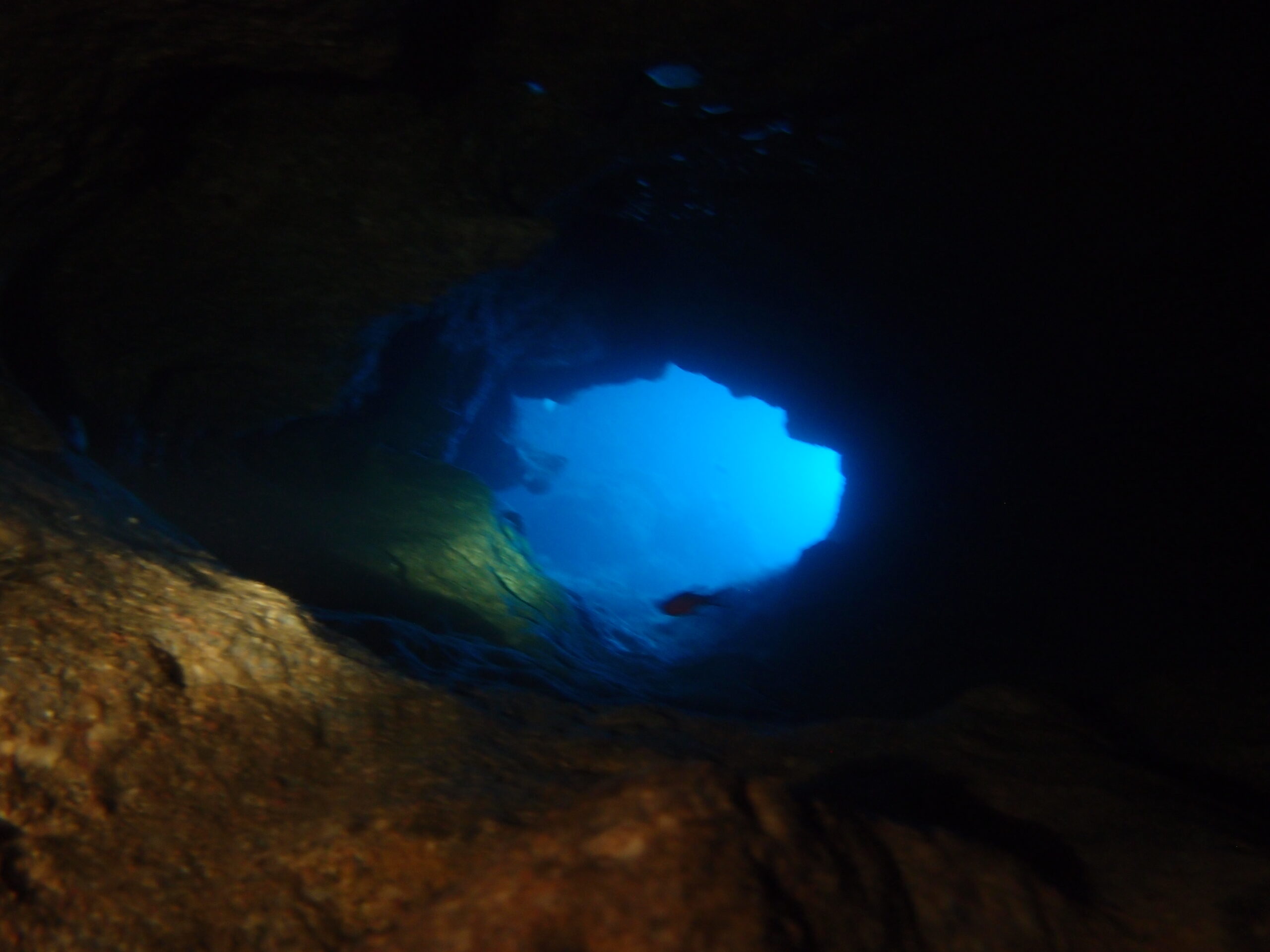 View through an underwater cave opening toward bright blue light