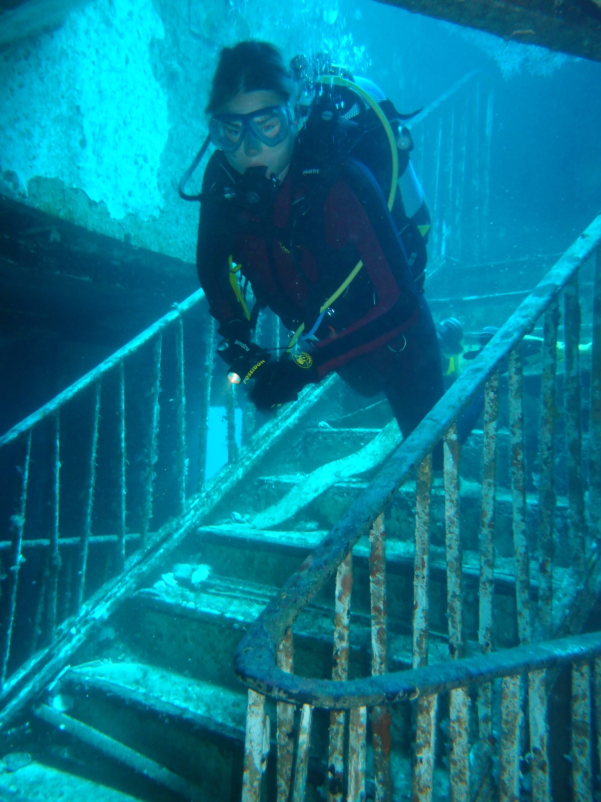 Diver descending a rusted staircase inside a sunken wreck