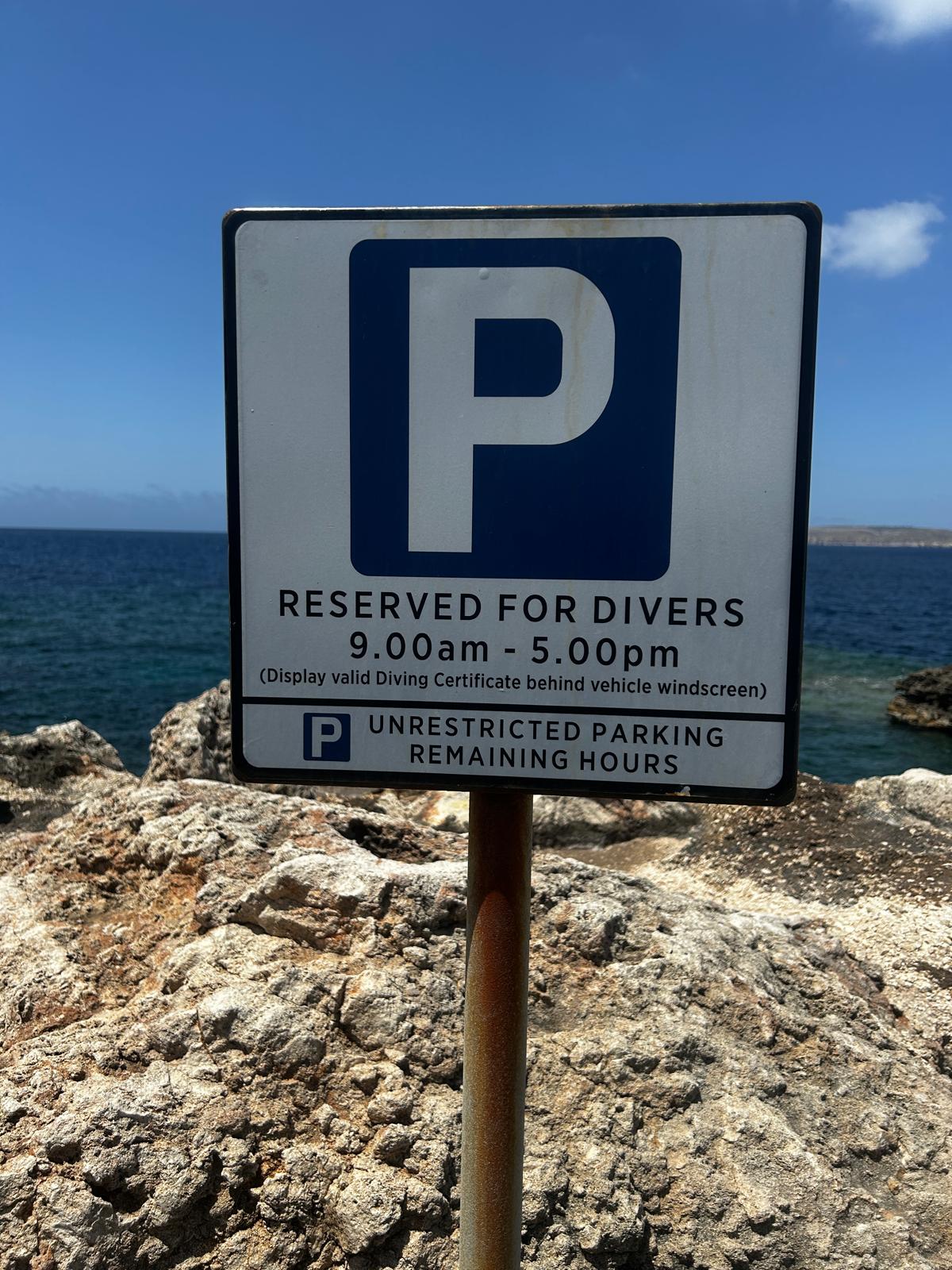 Road sign reading Reserved for Divers beside a rocky coastline