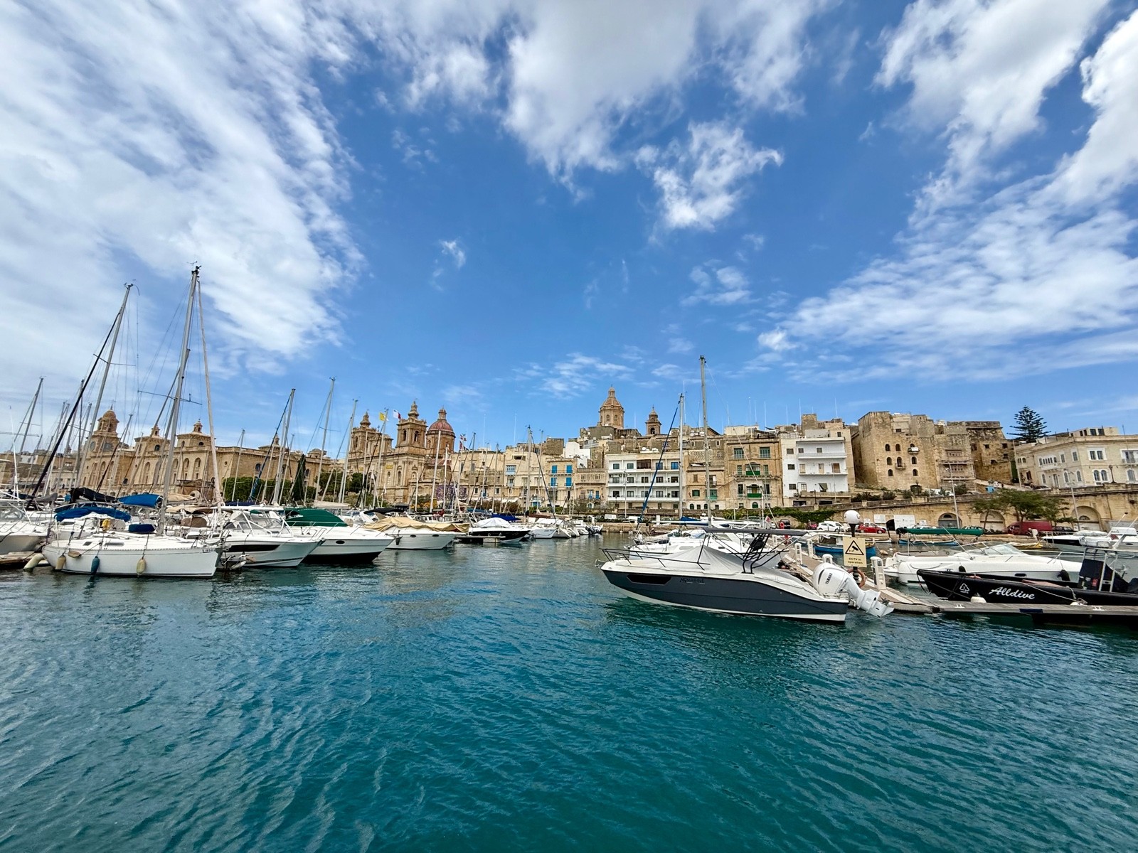 Marina full of boats with a domed church skyline in the background