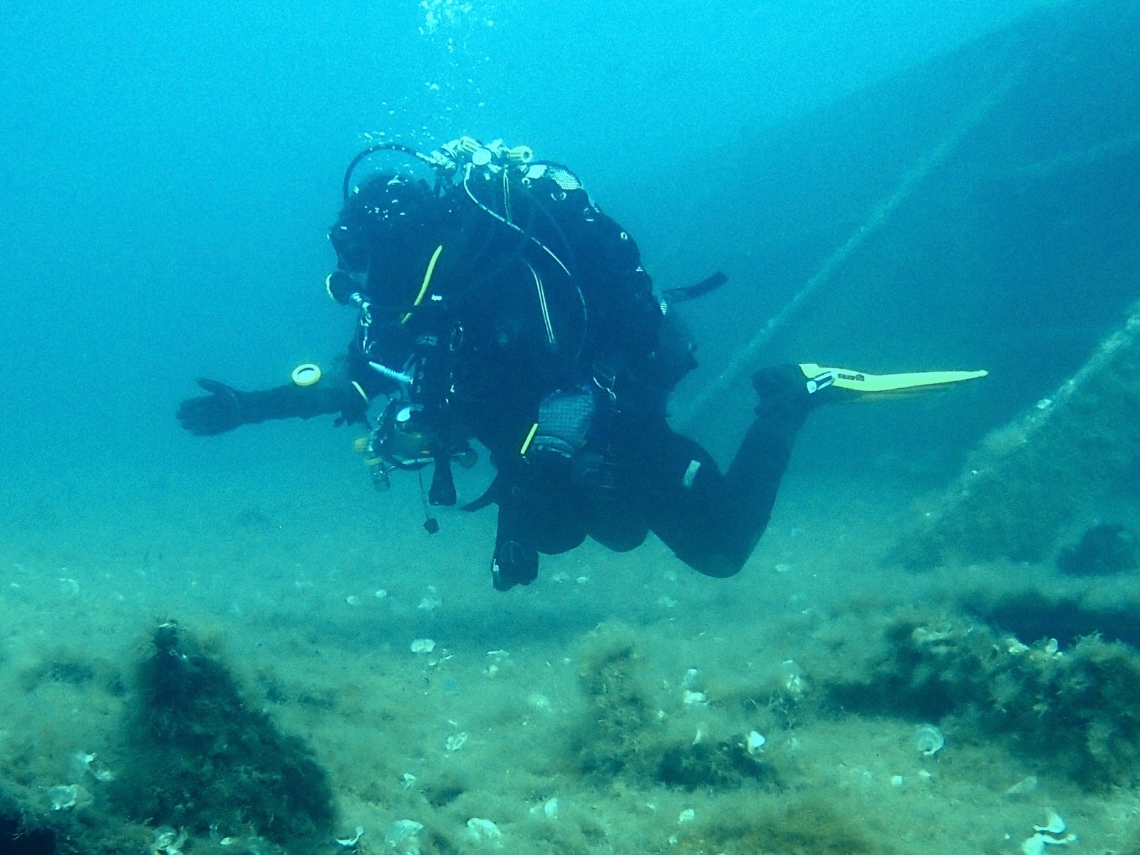 Tec diver with twin cylinders hovering beside a large wreck on the seabed