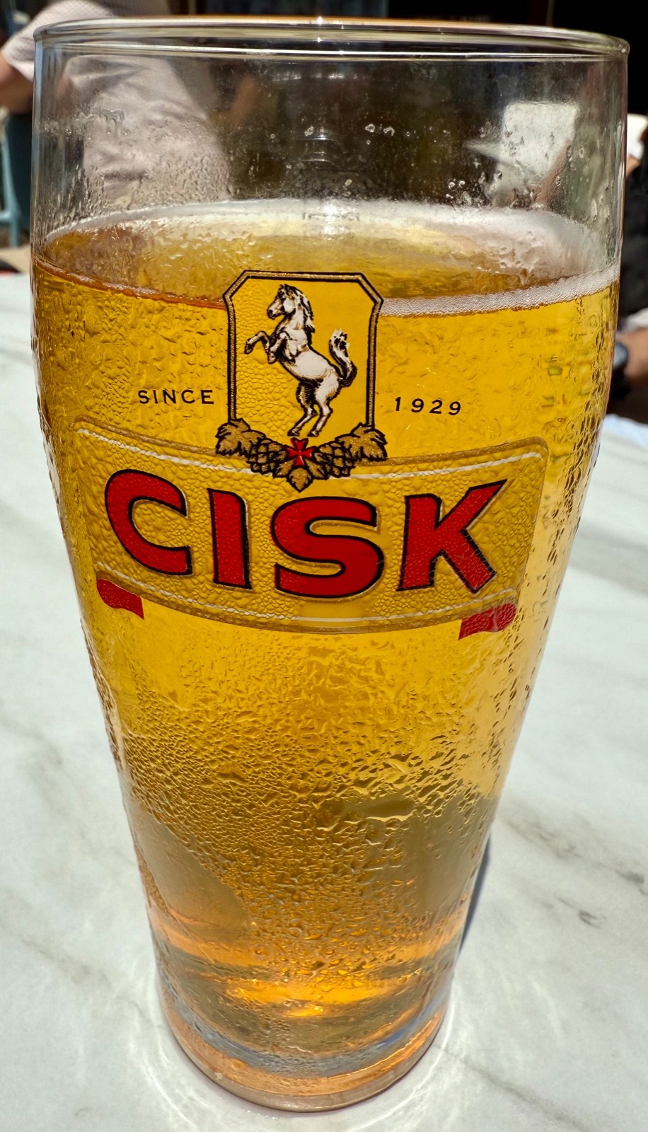 Close-up of a pint glass of Cisk lager on an outdoor table