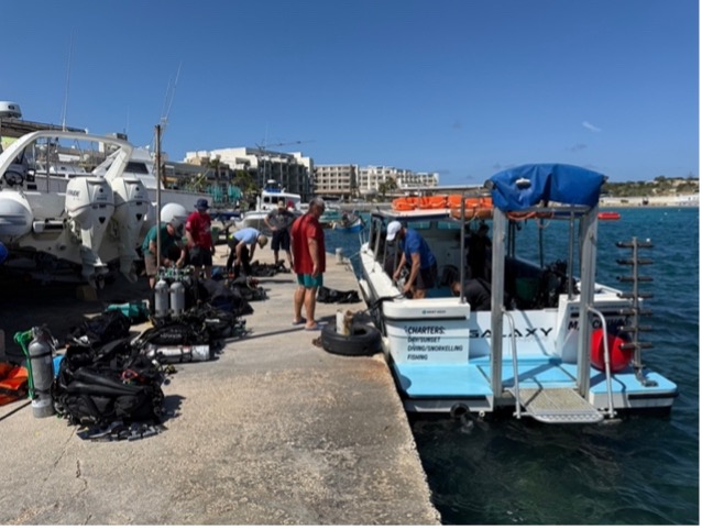 Divers loading equipment onto a dive charter boat at a harbour